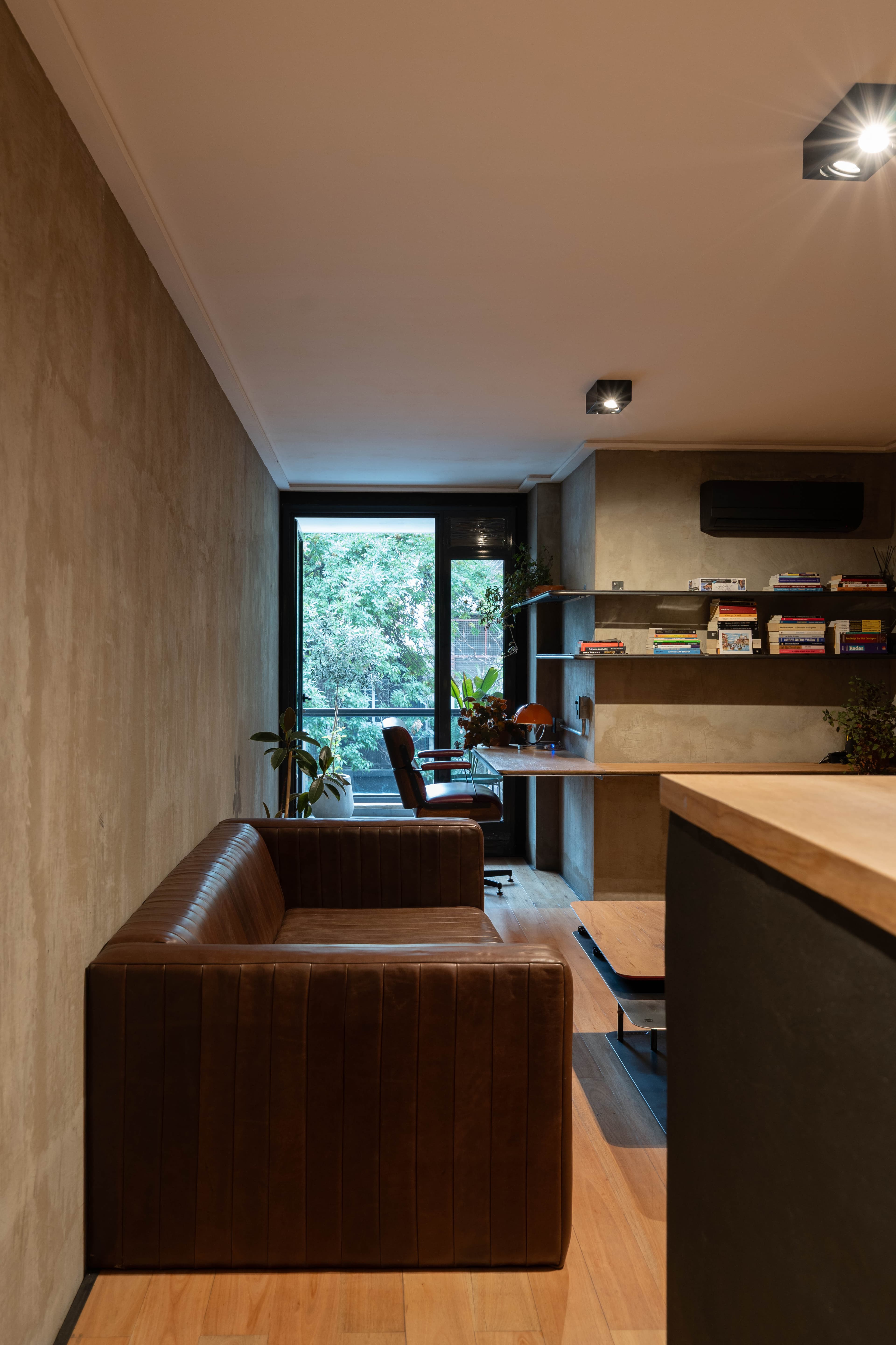 Vista del departamento desde el ingreso con sillón y zona de trabajo