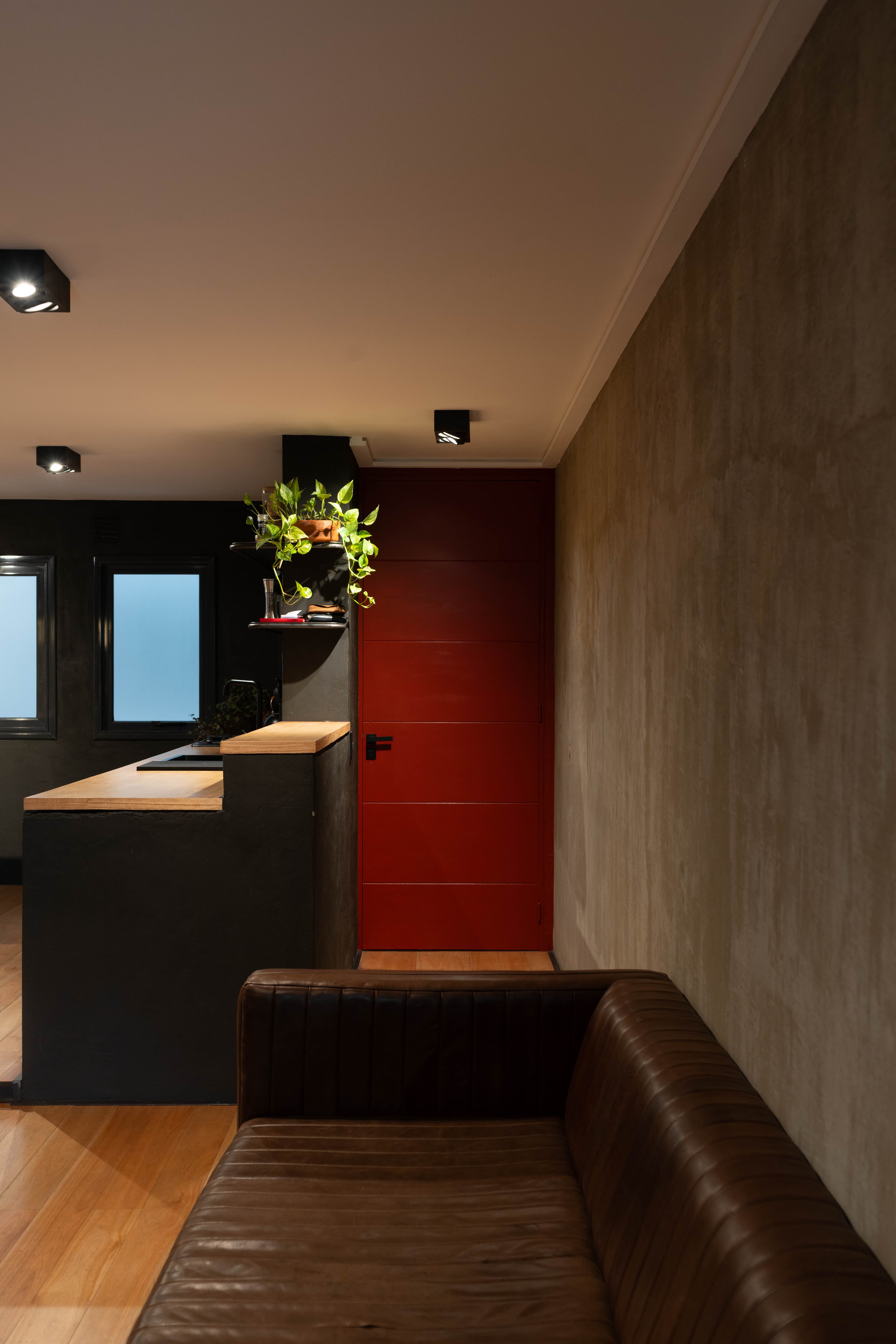 Ingreso al departamento con puerta roja y sillón de cuero
